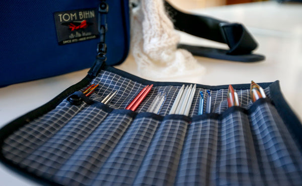 A Pen Tool Wrap filled with knitting supplies and connected to a bag using its snaphook.